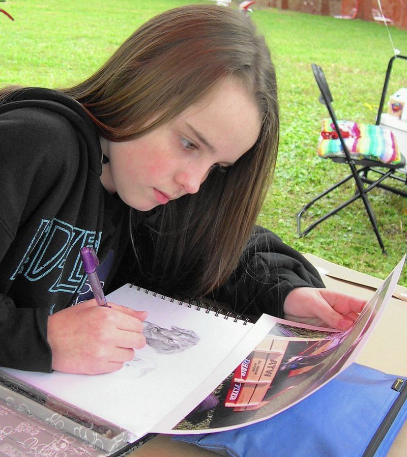 Photo of artist Chelsea Smith aged 12 at her first art show drawing an original pet portrait of two dogs